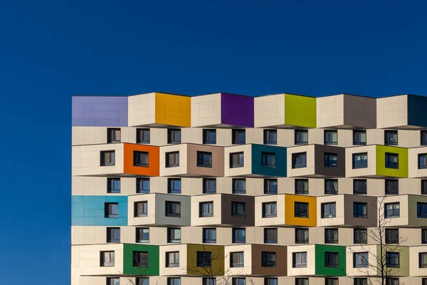 俄罗斯莫斯科 2020年12月8日 住宅区 绿色公园 蓝色天空背景上有五彩斑斓窗户的新住宅建筑的立面 房子的正面是五彩斑斓的 — 图库照片