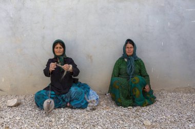Shiraz, İran - 11 Mayıs 2018: Qashqai göçebe kadınlar yün örüyorlar. Qasqhai geçici köylerde yaşayan göçebe insanlar..