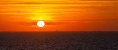 Gün batımında ufukta bir gemi.