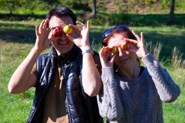 Sonbaharda yürüyüşe çıkan komik bir çift, erkek ve kadın küçük yaban elmalarıyla şakalaşıyor.