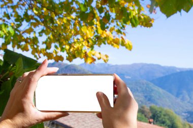 Dişi eller telefonla fotoğraf çeker. Güzel sonbahar manzarası dağlarda.