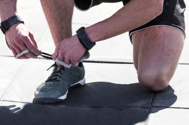 Açık havada CrossFit yarışması, bir sporcu ayakkabı bağı bağlar