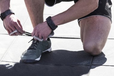 Açık havada CrossFit yarışması, bir sporcu ayakkabı bağı bağlar