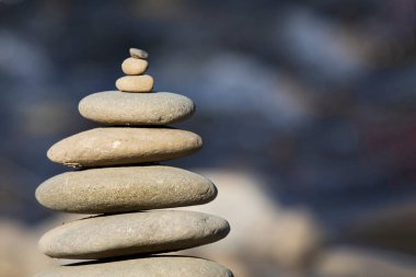 Bulanık arkaplanda nehir kıyısında kairn