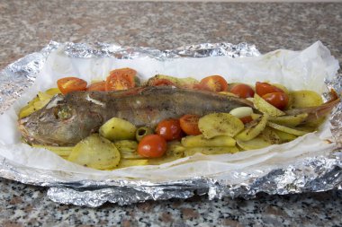 Patates, vişneli domates ve zeytinli folyoda pişmiş gurnard. Akdeniz mutfağı
