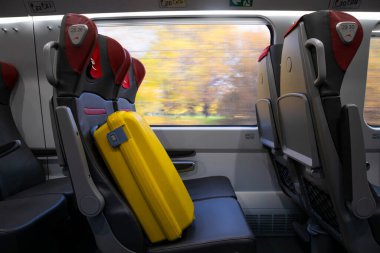 Tren yolculuğu konsepti. Trendeki koltukta sarı bavul.
