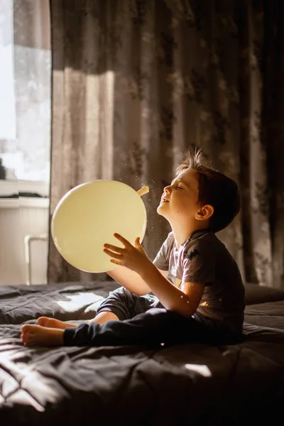Een Vijfjarige Jongen Zit Thuis Bank Met Een Ballon Spelen — Stockfoto