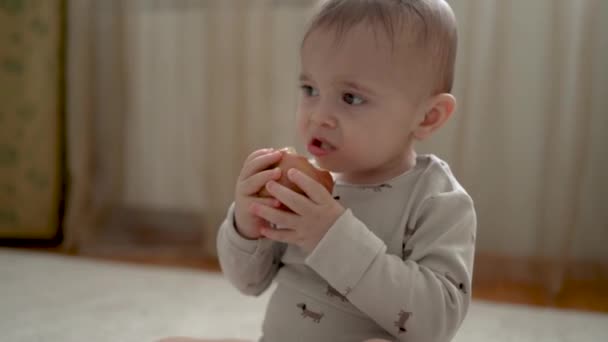 Bebek Evde Beyaz Bir Halıda Oturuyor Lezzetli Bir Elma Çiğniyor — Stok video
