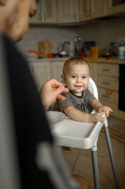 Babası mutfakta oğlunu lapa ile besliyor.