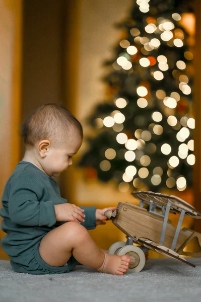 Criança Brinca Com Grande Avião Madeira Fundo Uma Árvore Natal — Fotografia de Stock