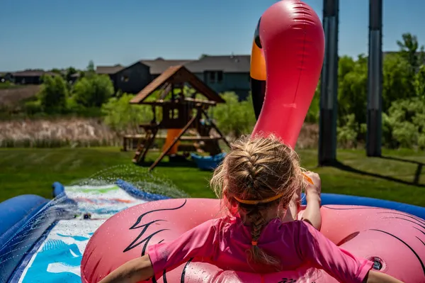 Gyerek megy le a csúszdán egy flamingó csőben — Stock Fotó