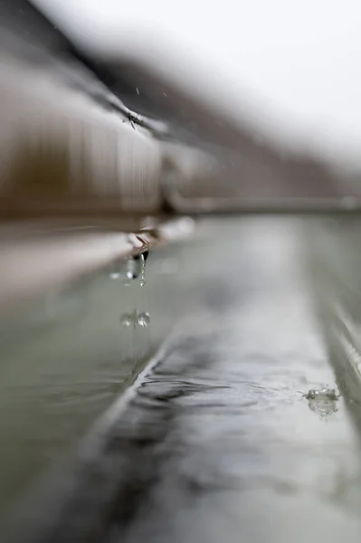 Селективный акцент на участке жилой канавы с вешалкой, передающей воду во время шторма. Капли дождя видны. — стоковое фото