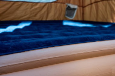 Doldurulan çadırın zeminindeki şişme şişme yatağın seçici odağı. 