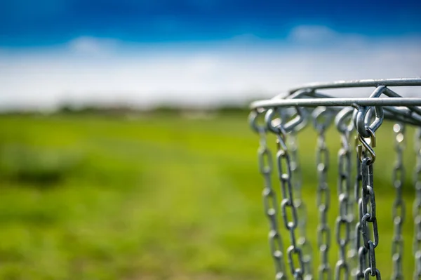 Cadenas de meta de golf de disco balanceándose suavemente en la brisa con un campo verde en el fondo —  Fotos de Stock