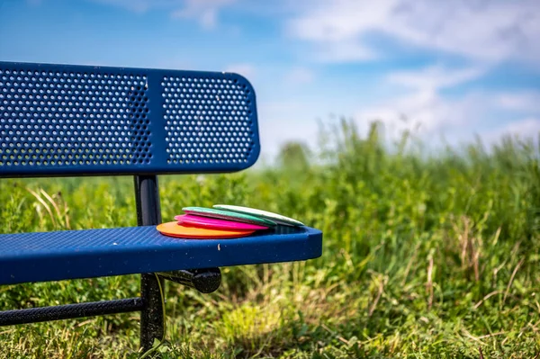 Hromada disků odpočívajících na lavičce v parku golfového hřiště — Stock fotografie