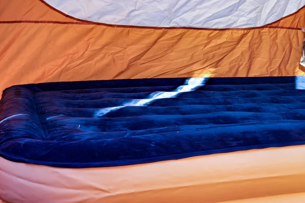 Foco seletivo de um colchão de ar inflável no chão de uma barraca que está sendo enchida. — Fotografia de Stock