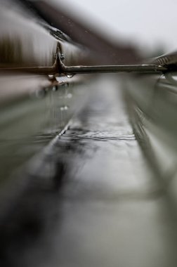 Kasırga sırasında su taşıyan bir hangarla iskan oluğunun seçici bir kısmına odaklan. Yağmur damlaları ve damlalar görünür.