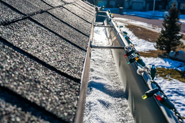 Gelo e neve acumulando-se dentro de um sistema de calha no telhado em uma casa residencial — Fotografia de Stock
