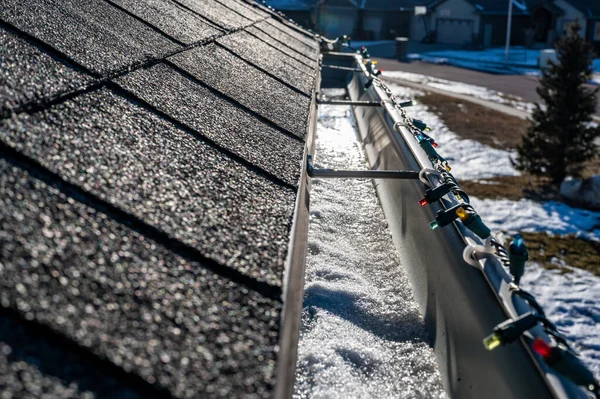 Gelo e neve acumulando-se dentro de um sistema de calha no telhado em uma casa residencial — Fotografia de Stock