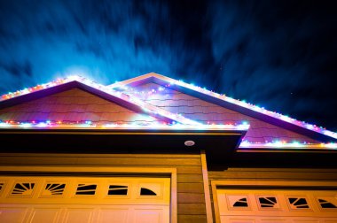 Rüzgardan kopmuş bir evin üzerine Noel ışıkları sarkmış..