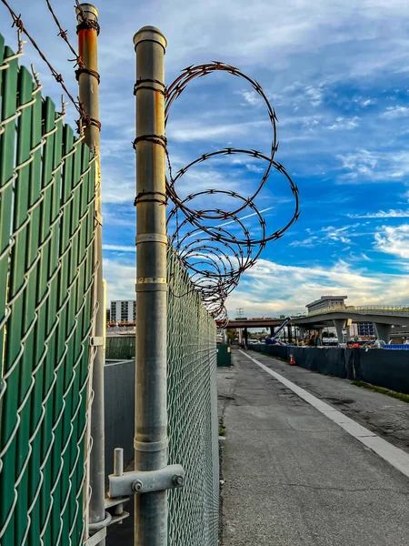 Barbed razor wire on top of slat chainlink fence in a construction zone — Stock Photo, Image