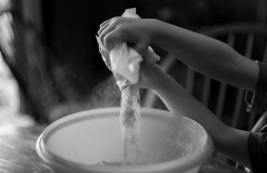 Küçük çocuk malzemeleri bir kaseye boşaltıyor ve havaya toz salıyor..