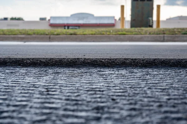 Enfoque selectivo de bajo ángulo en pavimentación de recubrimiento de asfalto en la parte superior de una base de hormigón de una calle residencial — Foto de Stock