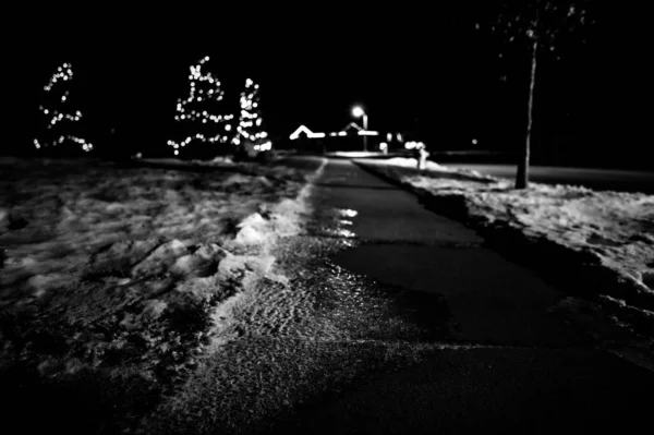 밤에 보도 위에 얼음 과 눈 이 있고, 가로등 이 탁한 표면에 반사되어 있다. — 스톡 사진