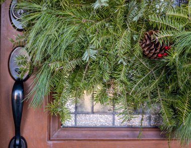 Dış kapı girişi saplı ve camların üzerinde yeşil tatil çelengi var..