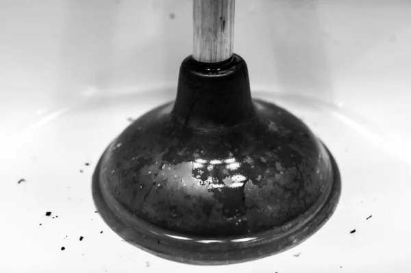 Using a plunger on a bathroom sink plugged with Hair and scum in a pool of stagnant standing water. — Stock Photo, Image