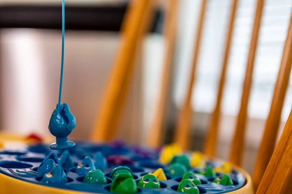 Childrens game of using a miniature pole and line lowered into open plastic fish to catch them as the pond spins. — Stockfoto