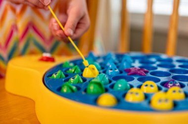 Çocuk oyununda minyatür bir sopa kullanılıyor ve gölet dönerken onları yakalamak için açık plastik balıkların içine çekiliyor.. 