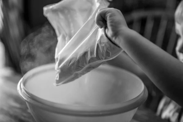 어린아이가 그릇에 원료를 버리면 먼지 가공 기위로 솟아오르게 된다. — 스톡 사진