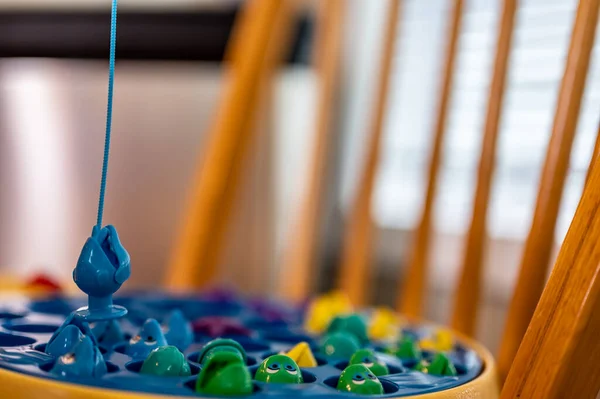 Childrens game of using a miniature pole and line lowered into open plastic fish to catch them as the pond spins. — Stockfoto