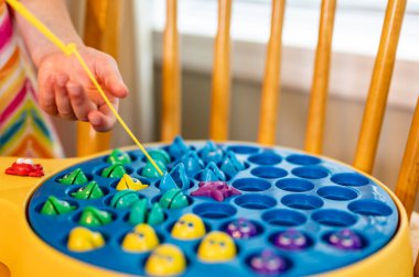 Çocuk oyununda minyatür bir direk kullanılıyor ve gölet dönerken onları yakalamak için açık plastik balıkların içine çekiliyor. - Evet. Yüksek kalite fotoğraf