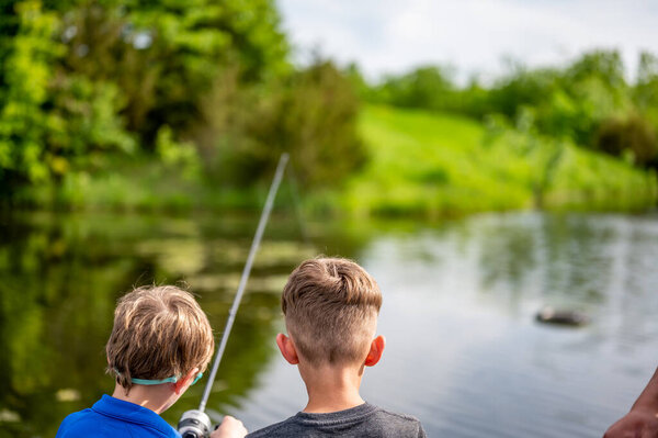 Двое молодых мужчин рыбачат на пруду. Высокое качество фото