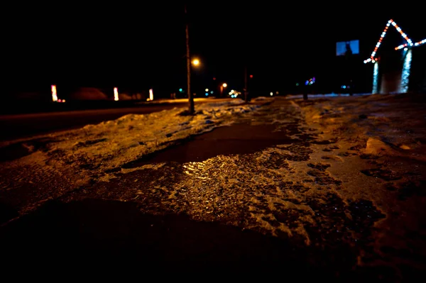 Ice and snow on a sidewalk at night with streetlight reflecting off the slick surface. High quality photo