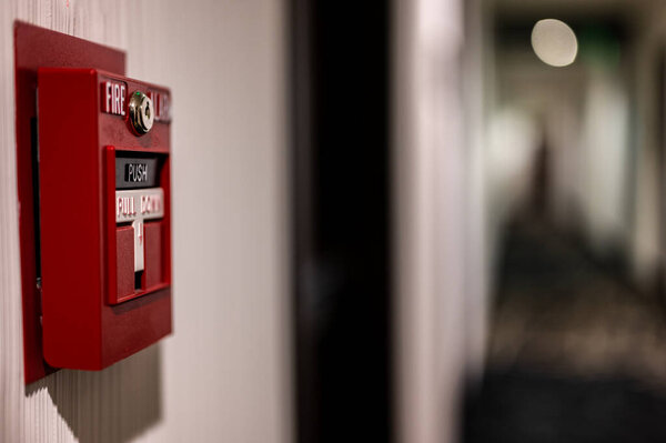 Выборочный фокус на настенном выключателе пожарной сигнализации в пустом коридоре. Высокое качество фото