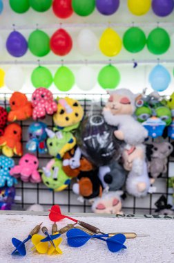 Bir oyuncunun panayırda kazanabileceği balon hedefleri ve ödüllerle dolu bir duvarda oturan dartlara odaklan. Yüksek kalite fotoğraf