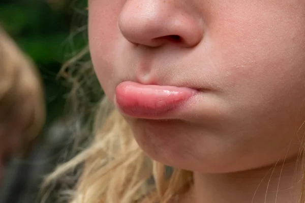 Close-up of a lower lip jutting out on a fussy girl that is pouting. High quality photo