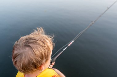 Boy on a fishing with blue water in background . High quality photo