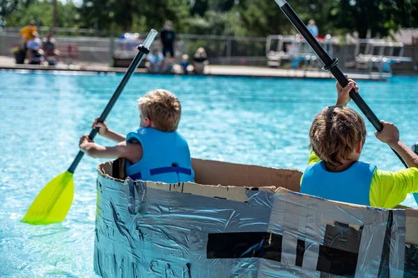 Two Boys Paddling Cardboard Boat Race Pool High Quality Photo — Stock Fotó