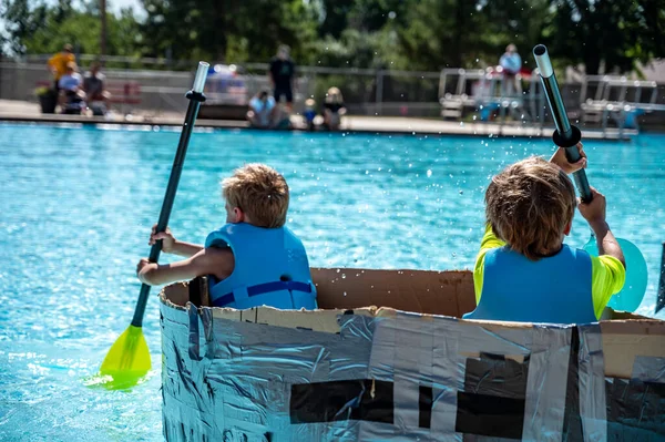 Two Boys Paddling Cardboard Boat Race Pool High Quality Photo — Stock Fotó