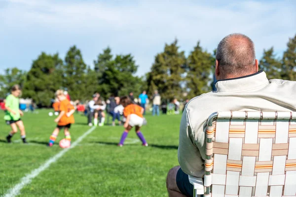 Grandpa watching his granddaughter playing soccer on a fall afternoon. High quality photo