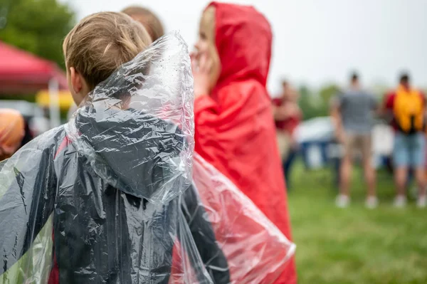 Young child with a clear plastic poncho to keep off the rain at a football game. . High quality photo