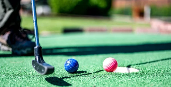 Mini golf game with several colored balls in the way of a putter lined up. High quality photo