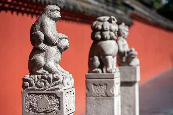 Trois statues et un mur rouge dans le monastère de Wenshu Image En Vente