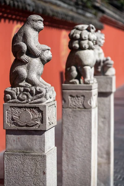 Trois statues et un mur rouge dans le monastère de Wenshu Photo De Stock