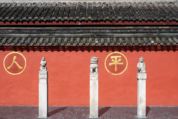 Trois statues et un mur rouge dans le monastère de Wenshu Photo De Stock