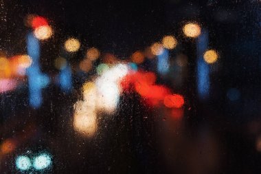 Gece ıslak bir pencerenin arkasından araba trafiği